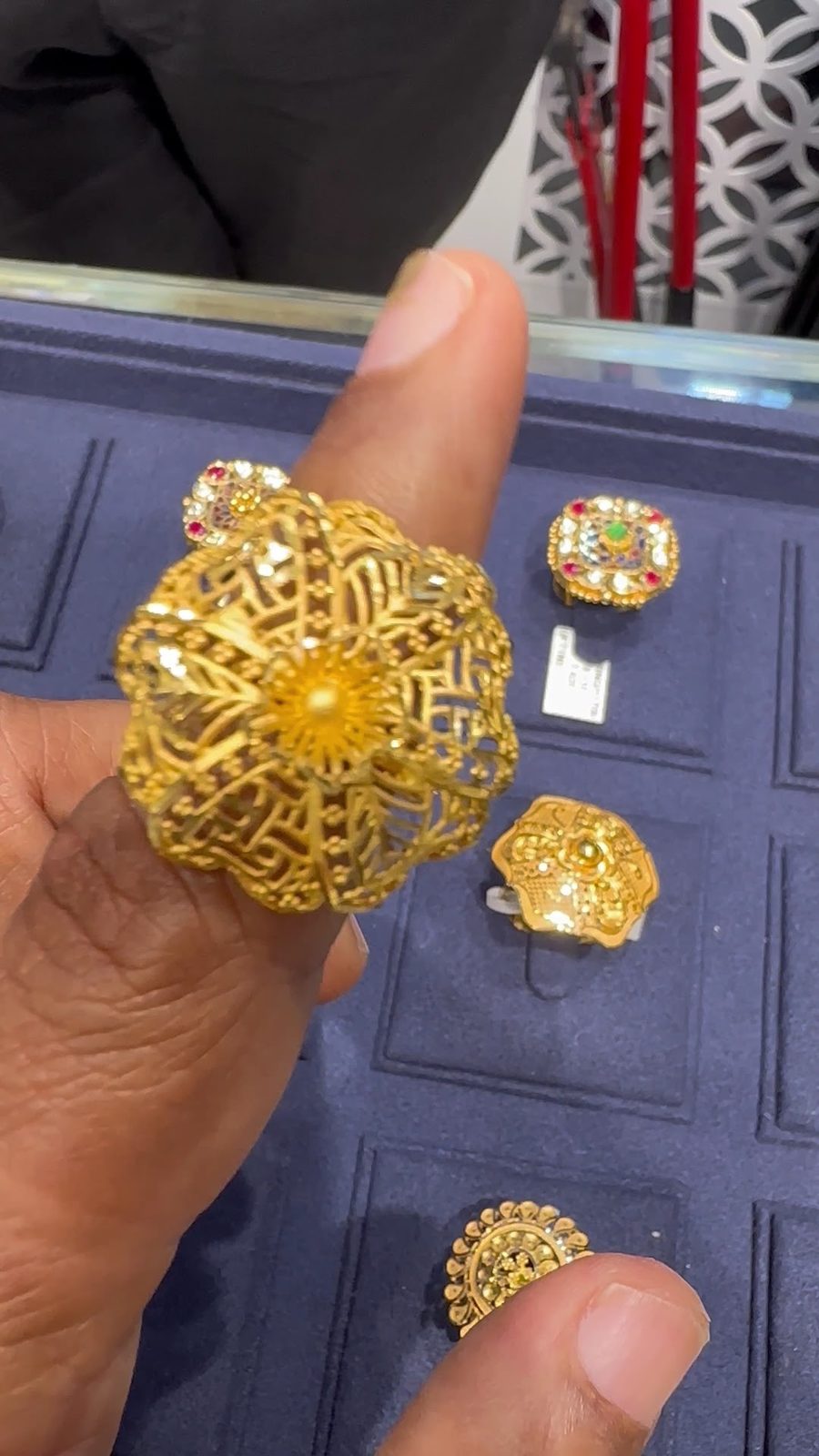 Filigree gold ring over a navy tray